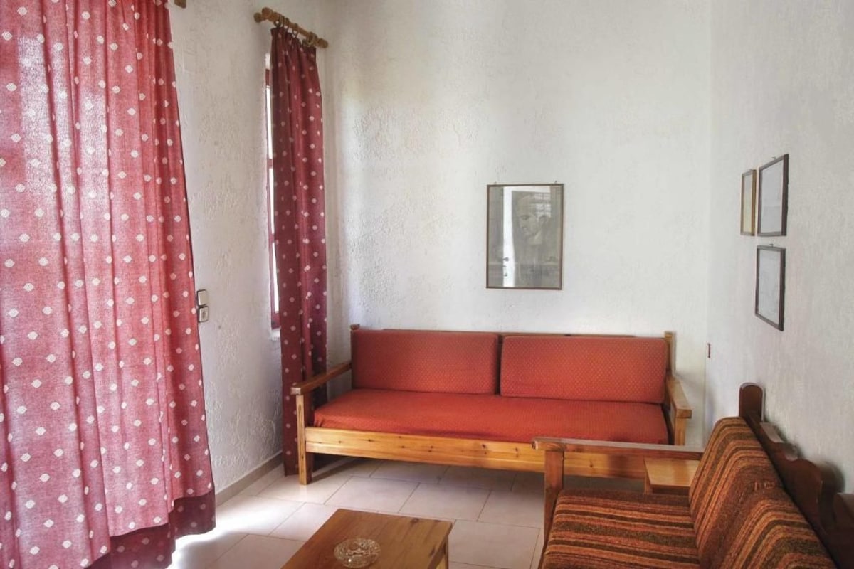 A room with a wooden sofa, a small table, and a patterned curtain.