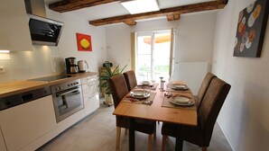 Une cuisine moderne avec un coin repas, des poutres apparentes en bois au plafond et une grande fenêtre.
