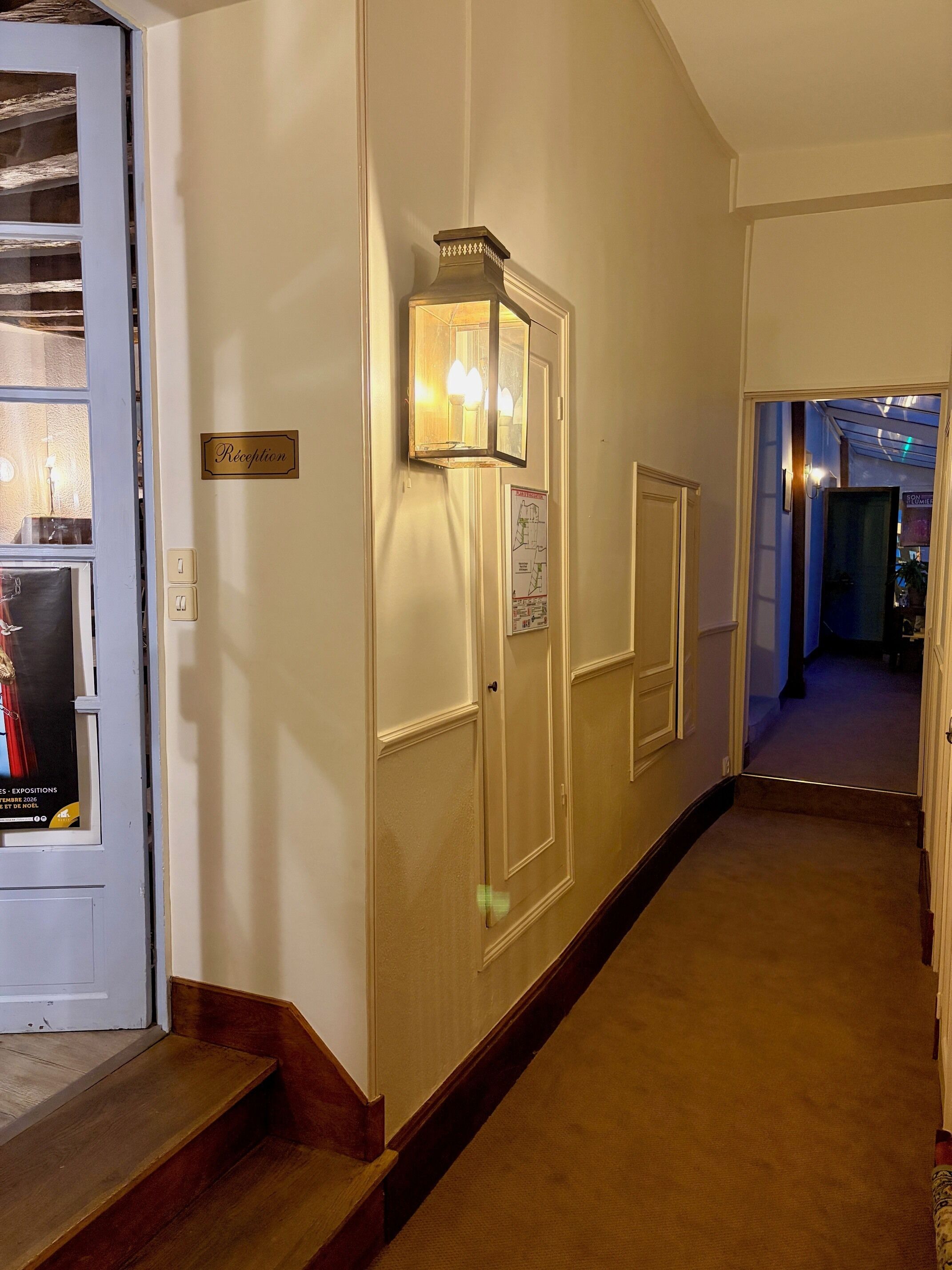 A reception area with a sign, a wall-mounted light fixture, and a poster.
