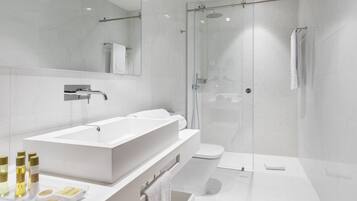 Un baño moderno con un lavamanos grande blanco, una cabina de ducha de vidrio y un inodoro.