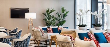 A modern lounge area with a checkered floor, wicker furniture, and a flat-screen TV mounted on the wall.