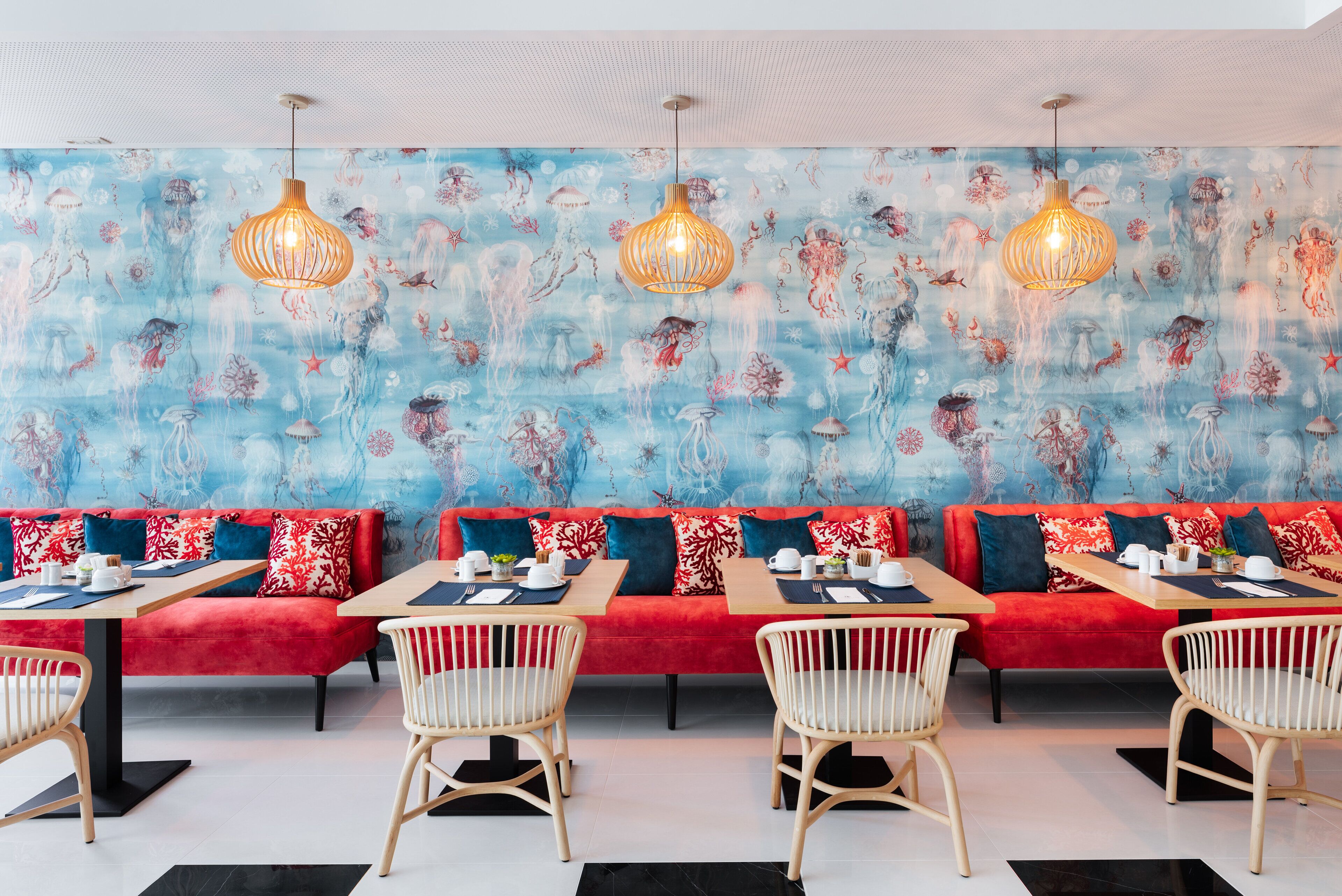 Een restaurant met een levendige blauwe en rode muurschildering, houten tafels en rieten stoelen.