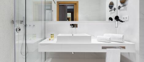 A modern bathroom with a glass shower enclosure, a white sink, and a mirror with two round mirrors above it.