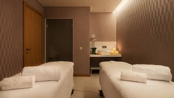 Two single beds with neatly folded towels, minimalist design, and subtle geometric patterned walls.