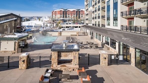 An outdoor patio with stone seating, a fire pit, and a pool area. - A/C, Pool, Slopeside, Hot Tub, Elevator, Ski Locker, In Unit Washer/Dryer (Steamboat Springs)