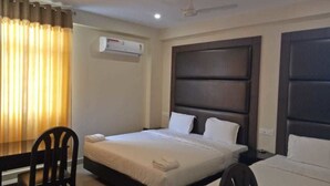 Quarto de hotel com cama, escrivaninha e cadeira. Há um ar condicionado na parede.