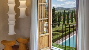 A room with a large window, a view of a pool, and two hanging lamps. - Casa Ruffino (Bagno a Ripoli)
