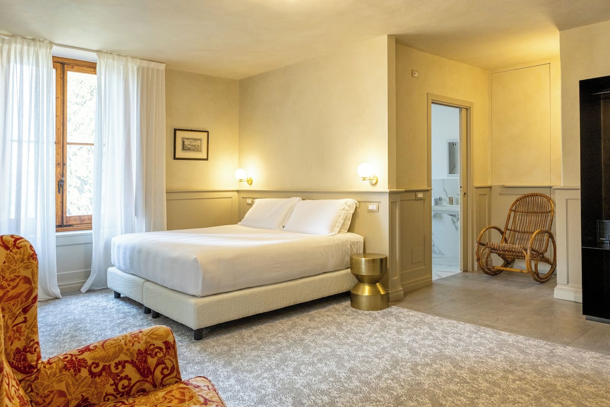 A bedroom with a bed, a chair, and a small table.