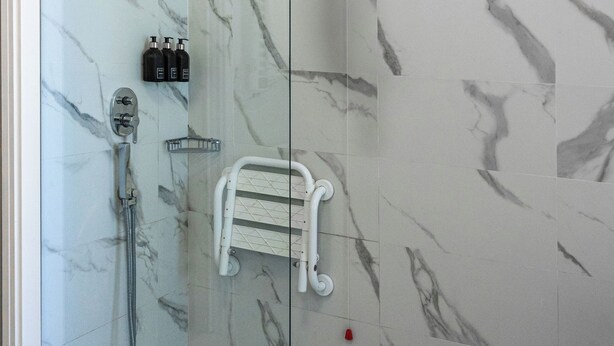 A glass-enclosed shower with a handheld showerhead, a handheld shower attachment, and a white towel rack. - Casa Ruffino (Bagno a Ripoli)