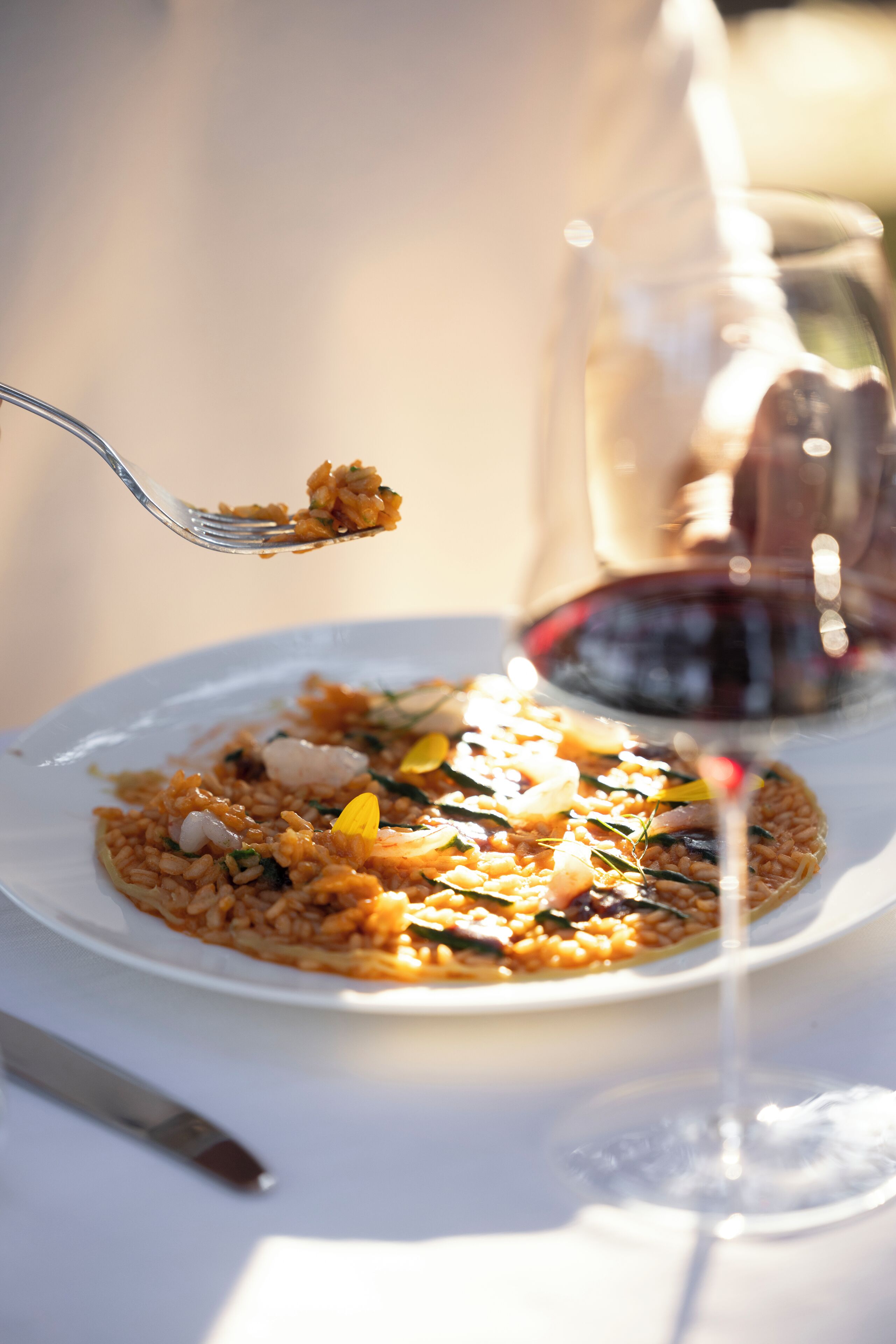 A plate of food with a fork and a glass of red wine.