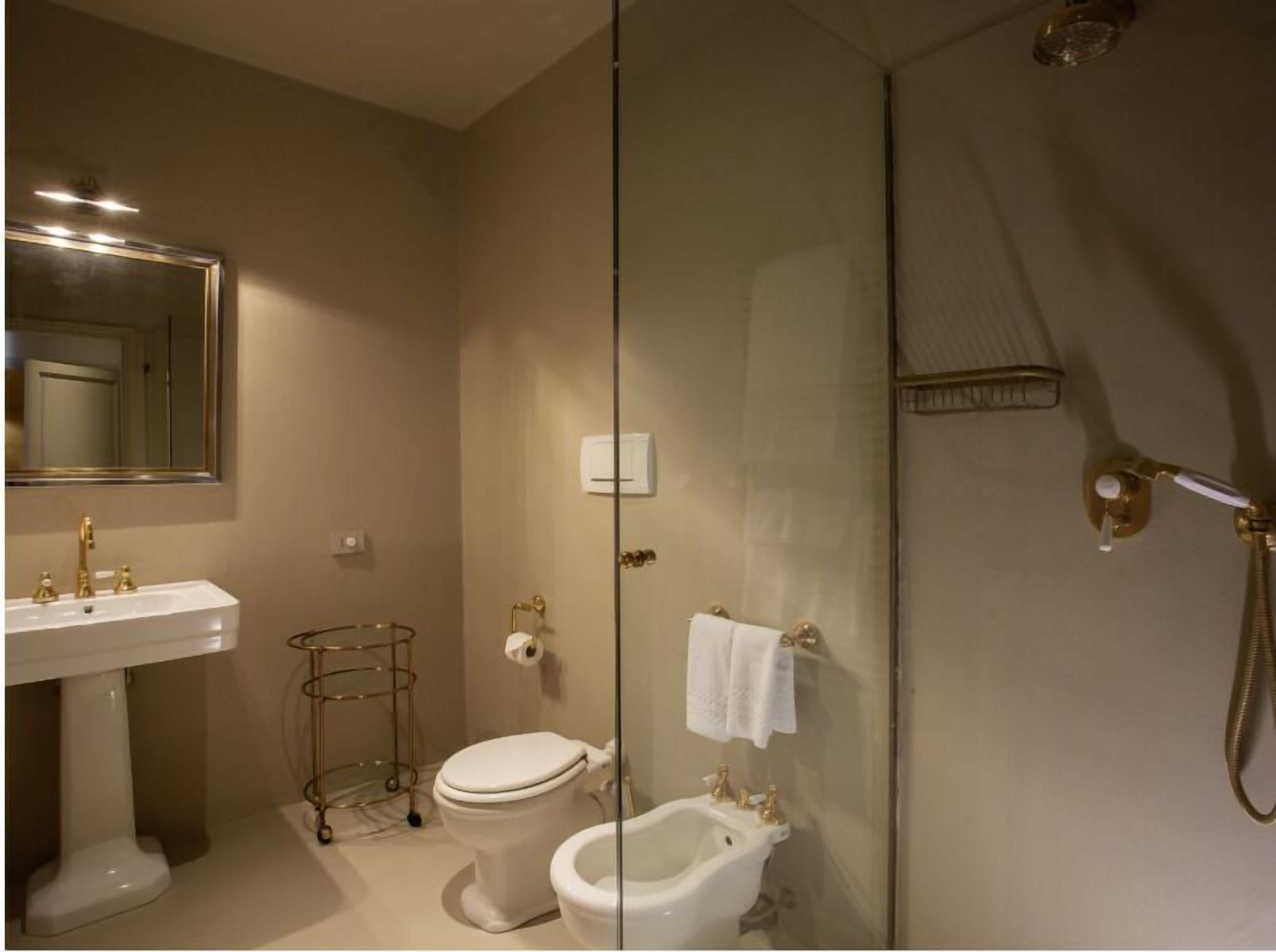 A bathroom with a pedestal sink, a toilet, a bidet, and a shower enclosure.