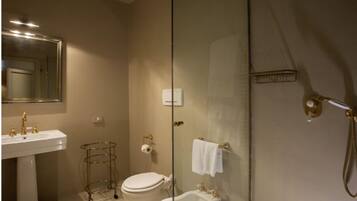 A bathroom with a pedestal sink, a toilet, a bidet, and a shower enclosure.