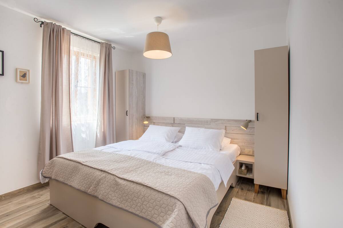 A neatly arranged bedroom with a bed, bedside tables, and a wardrobe.