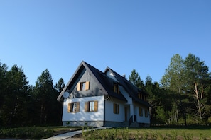 A two-story house with a sloped roof, wooden shutters, and a visible satellite dish. - The Starlings Apartments (Plitvicka Jezera)