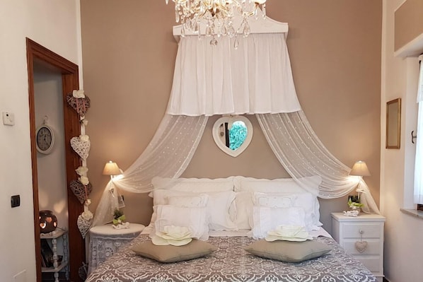 Un dormitorio con cama con dosel, mesitas de noche, un reloj y elementos decorativos.