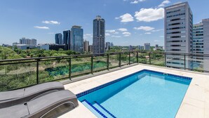 A rooftop pool with a city skyline view, surrounded by a glass railing. - Victoria Village (Asunción)