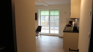 A small kitchen with a dining area, a window with blinds, and a view of the outside. - Ferienwohnung Remise (Lübbenau/Spreewald)