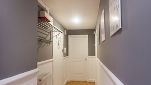 A narrow hallway with a wooden floor, a white door at the end, and a radiator on the left. - Keysan House 1 (London)