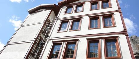 A multi-story building with a white facade and brown window frames.