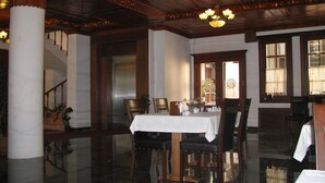 A dining area with a polished floor, a table set with chairs, and a chandelier.