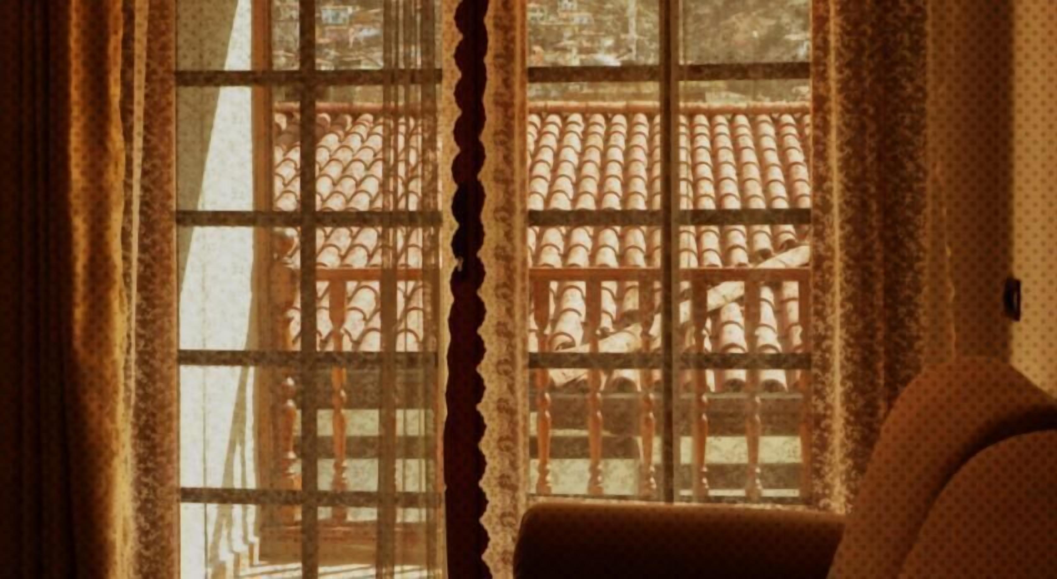 Une pièce dotée d’une fenêtre ornée d’une grille métallique décorative et de rideaux.
