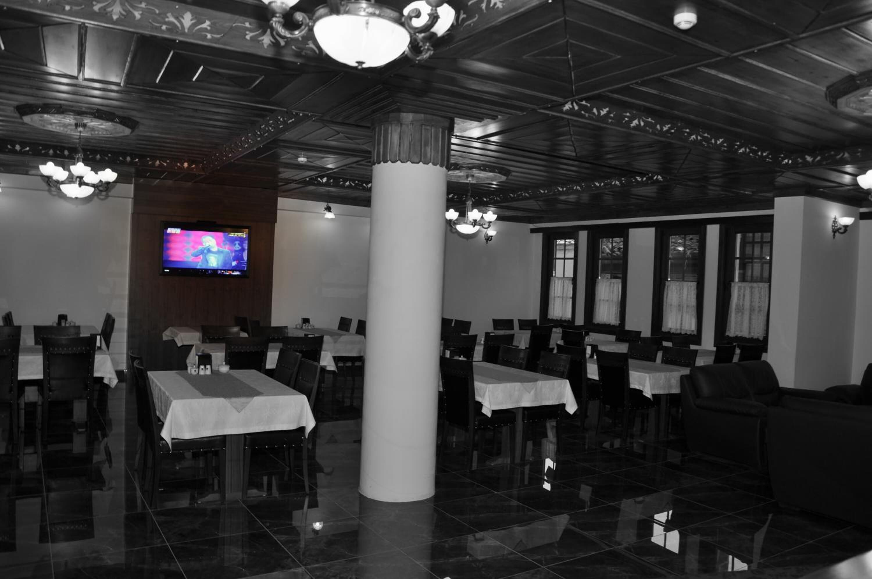 Un restaurante con una decoración moderna, que presenta un pilar grande, varias mesas y una pantalla de televisión mostrando un programa.