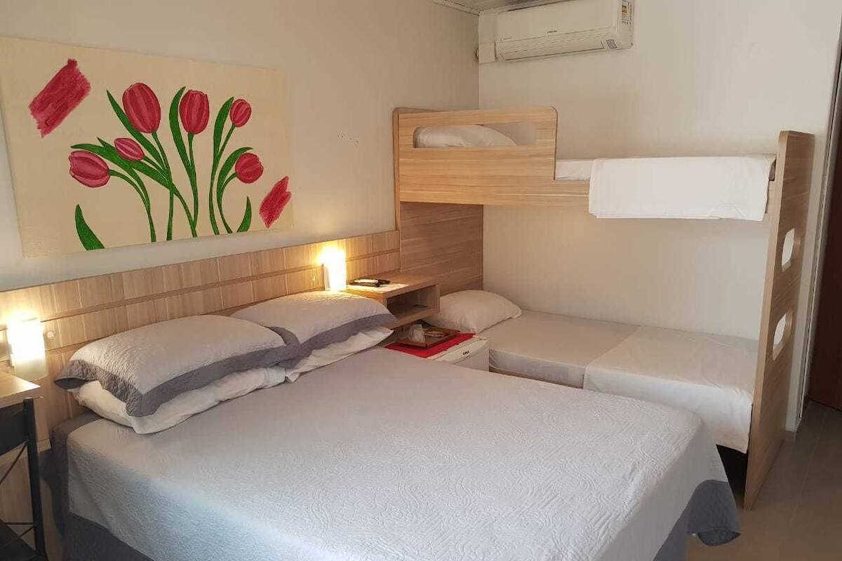 A bedroom with two beds, a wooden headboard, a nightstand, and a wall painting of tulips.