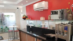 A modern kitchen with a red accent wall, stainless steel appliances, and a glass enclosure for the coffee machine. - Tulipa Hotel (Torres)