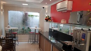 A modern kitchen with a red accent wall, a large window, and a dining area with two tables and chairs. - Tulipa Hotel (Torres)