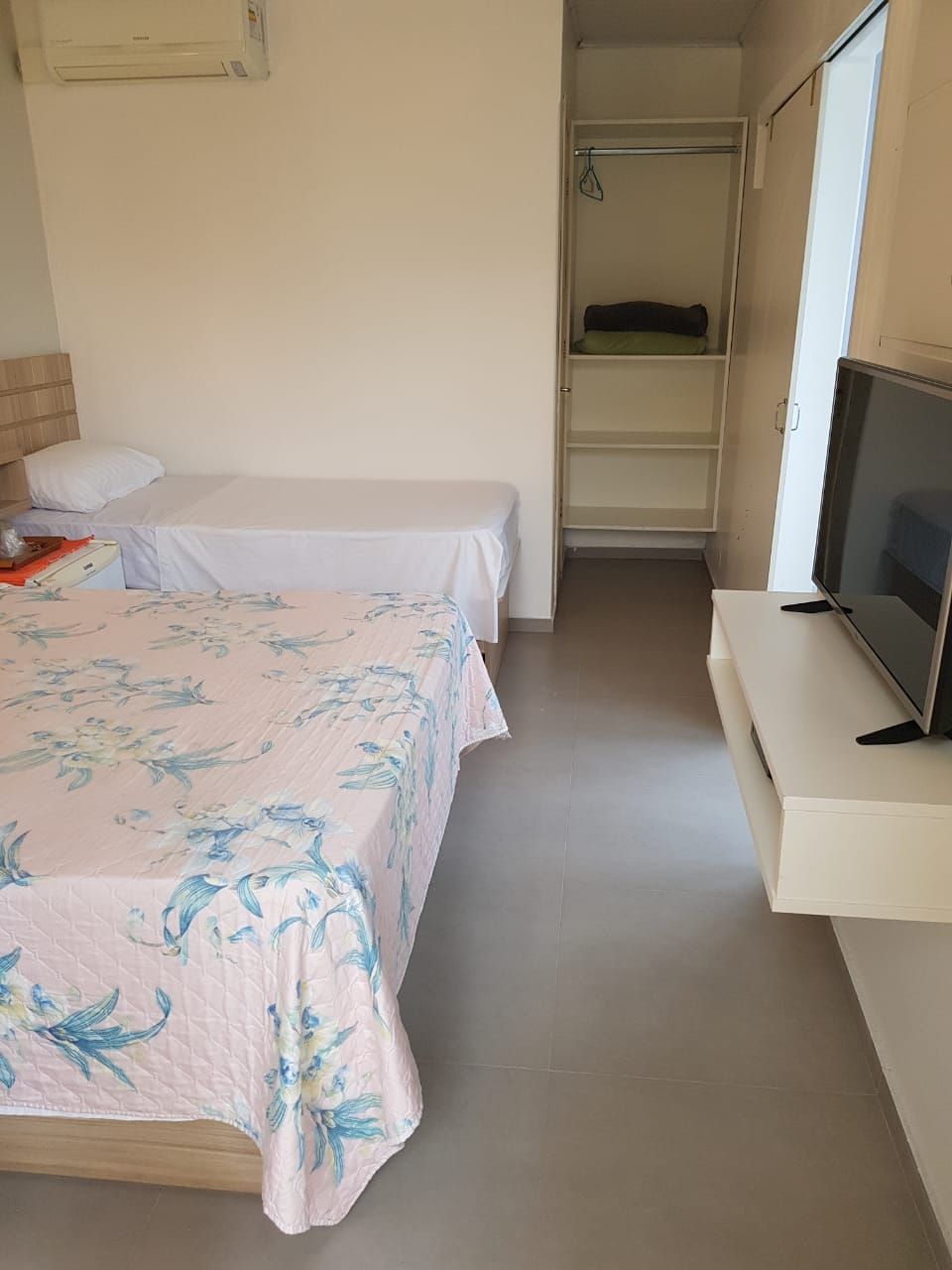 A bedroom with two beds, a television, and a wardrobe.