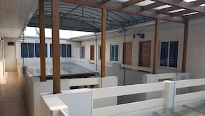 A covered outdoor area with a glass floor, wooden beams, and white railings. - Tulipa Hotel (Torres)