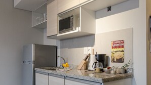 Moderni keittiö, jossa on ruostumattomasta teräksestä valmistetut kodinkoneet, mikroaaltouuni ja kahvinkeitin.