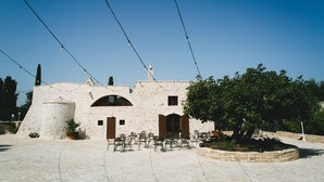 A stone building with a courtyard, outdoor seating, and string lights. - San Marco Antico Relais (Bitonto)