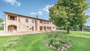 A stone building with a courtyard, a large tree, and a well-maintained lawn. - Casale Villa Chiara (Torgiano)