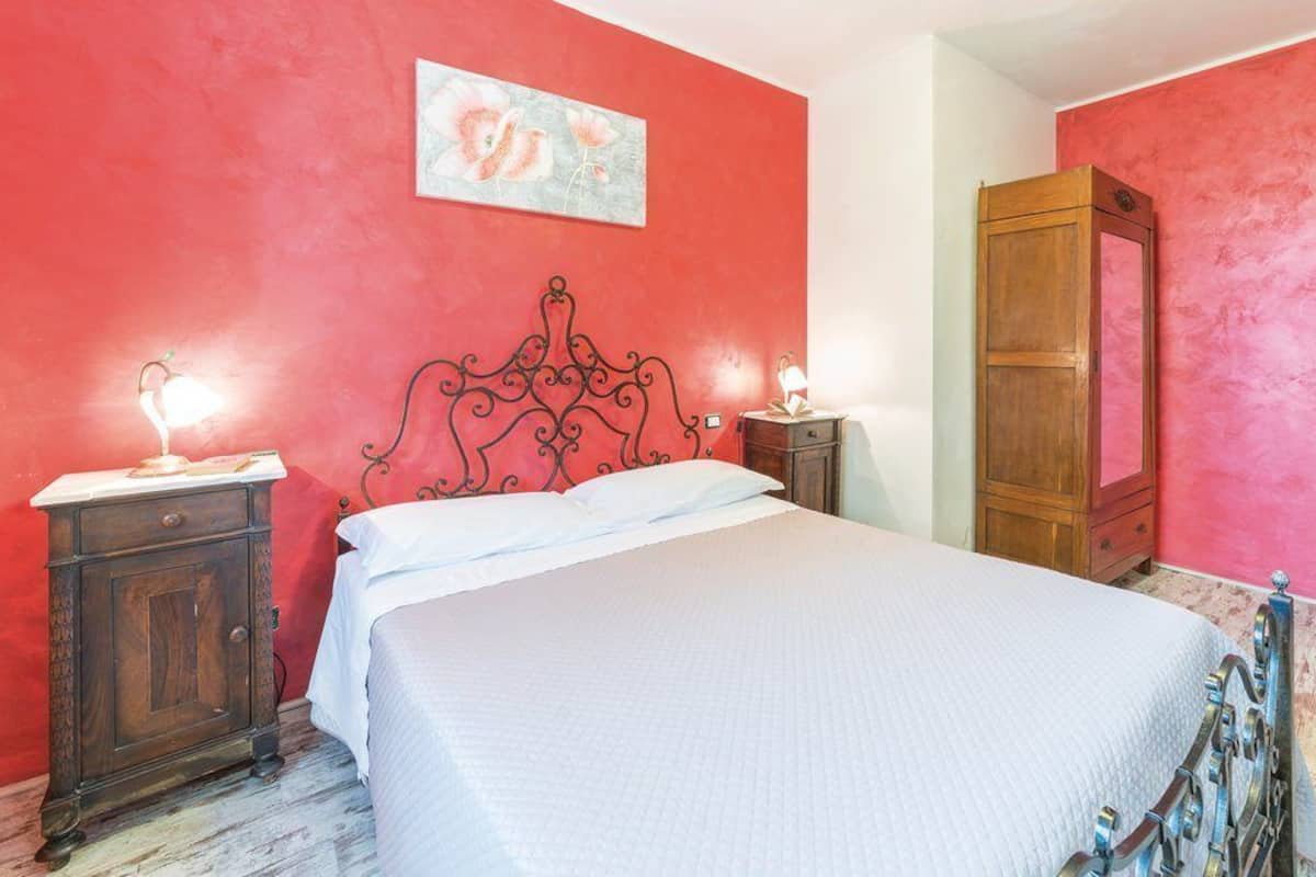 Une chambre à coucher comprenant un lit, deux tables de chevet, une commode, une armoire en bois et un tableau accroché au mur.