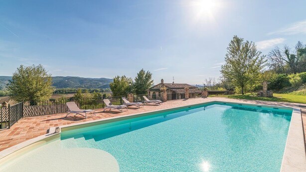 A rectangular swimming pool with clear blue water, surrounded by a brick deck and lounge chairs. - Casale Villa Chiara (Torgiano)