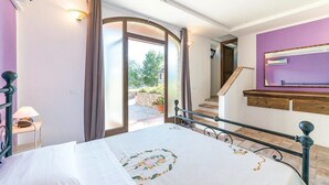 A bedroom with a bed, a nightstand, a mirror, and a staircase leading to an outdoor area. - Casale Villa Chiara (Torgiano)
