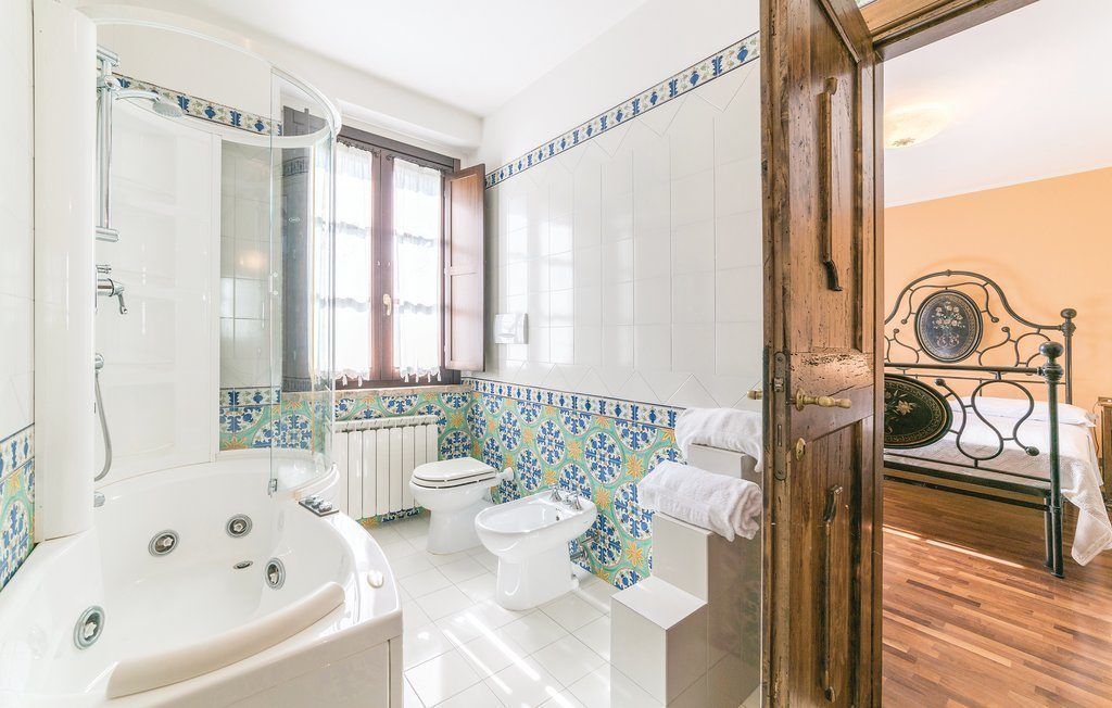 A bathroom with a bathtub, toilet, and bidet. There is a wooden door leading to another room.