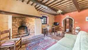 A rustic interior with a stone fireplace, wooden furniture, and a patterned rug. - Casale Villa Chiara (Torgiano)