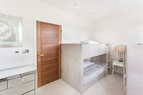 A bunk bed with a desk and lamp, a wooden door, and a framed picture on the wall. - Keysan House 2 (London)
