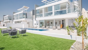 Uma casa moderna com dois andares, varanda de vidro ampla, piscina e área de estar ao ar livre.