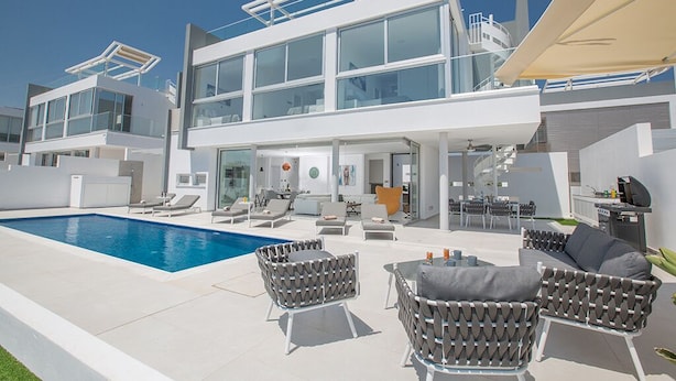 Uma casa moderna de dois andares com piscina, área de estar ao ar livre e um alpendre.