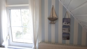 A room with a large window, a radiator, and striped walls. - Ferienwohnung Amsel (Lübbenau/Spreewald)