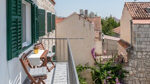 A balcony with a table and chairs, a potted plant, and a view of neighboring buildings. - Wind Rose Split (Split)