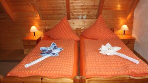 A wooden cabin room with two beds, each with a pillow and a lamp.