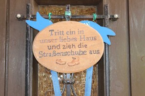 Une enseigne en bois, ornée d’un texte et d’une illustration de chaussure, est suspendue à une structure métallique.