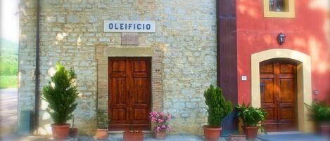 Um edifício com fachada de pedra e portas de madeira com a inscrição "OLEIFICIO".