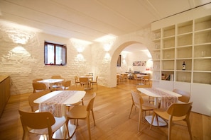 A cozy dining area with wooden tables and chairs, stone walls, and a wine rack. - RossoPorpora Agriturismo Colle Cardinale (Perugia)