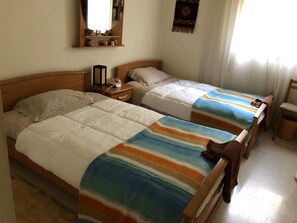 A bedroom with two single beds, a nightstand, a mirror, and a small shelf with decorative items. - Splendid Valley & Sea View (Broumana)