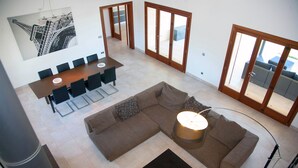 A spacious living area with a large sectional sofa, a dining table with chairs, and a modern lamp. - Modern house with large pool  (Búger)